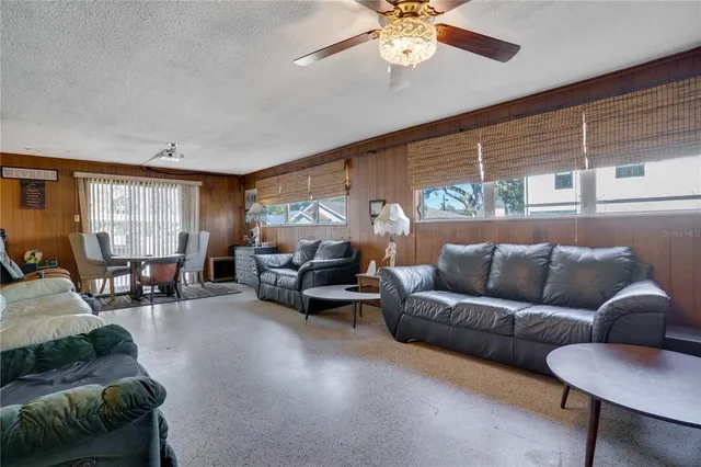 a living room with furniture and three large window