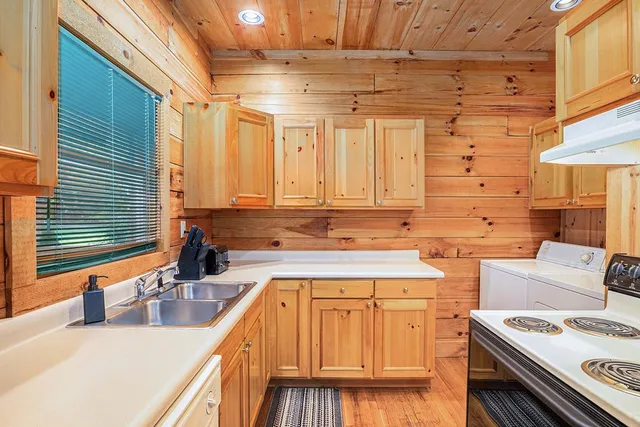 a kitchen with stainless steel appliances granite countertop a sink a stove and a wooden cabinets