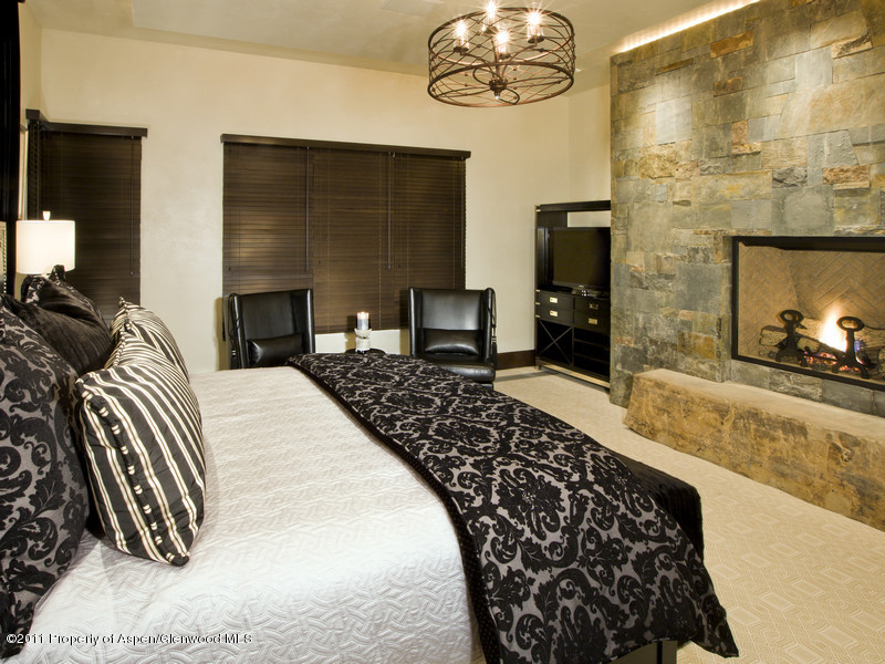675 Aspen Alps Road South Aspen, CO 81611 - Photo 21 of 37 a bedroom with a bed and a fireplace with the wooden floor