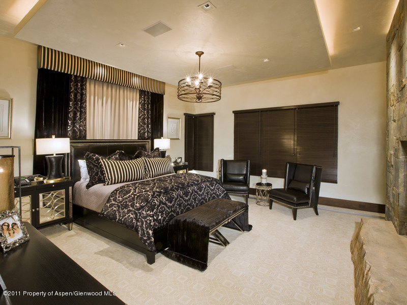 675 Aspen Alps Road South Aspen, CO 81611 - Photo 22 of 37 a spacious bedroom with a bed and a chandelier