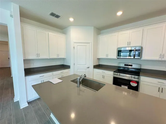 a kitchen with granite countertop a sink stove and cabinets