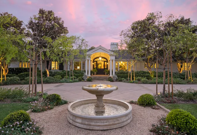 a view of a house with fountain in backyard
