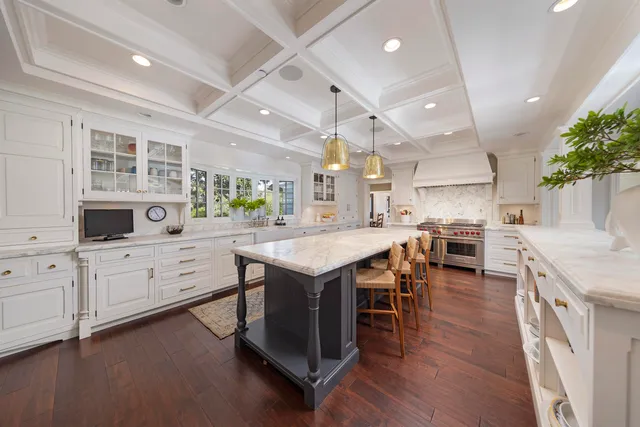 a kitchen with stainless steel appliances kitchen island granite countertop a stove top oven a sink a dining table and chairs with wooden floor