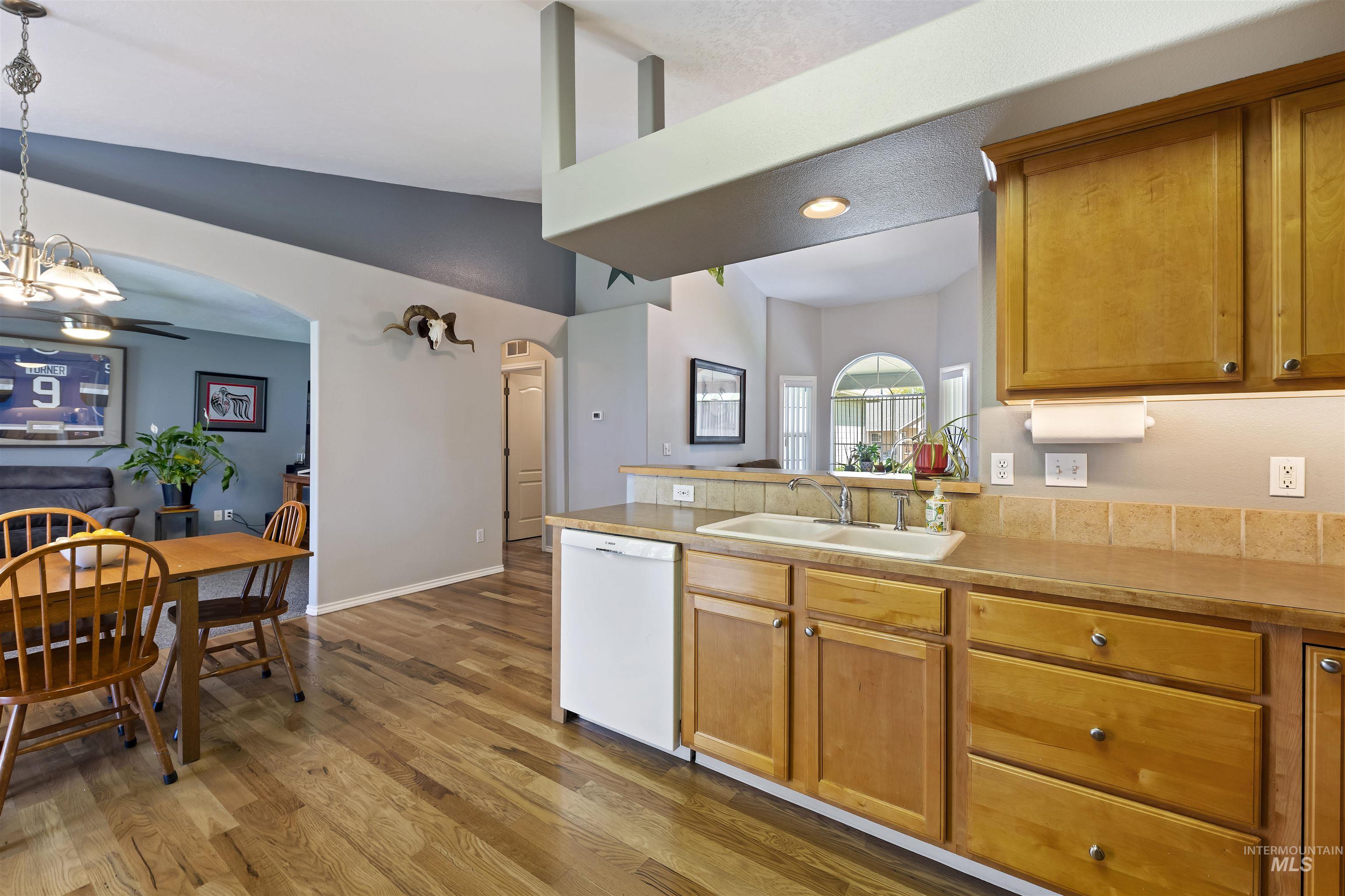2175 North CapeCod Way Meridian, ID 83646 - Photo 13 of 23 Kitchen featuring wood-finish flooring, natural wood cabinetry, light-toned countertops, and a tile backsplash