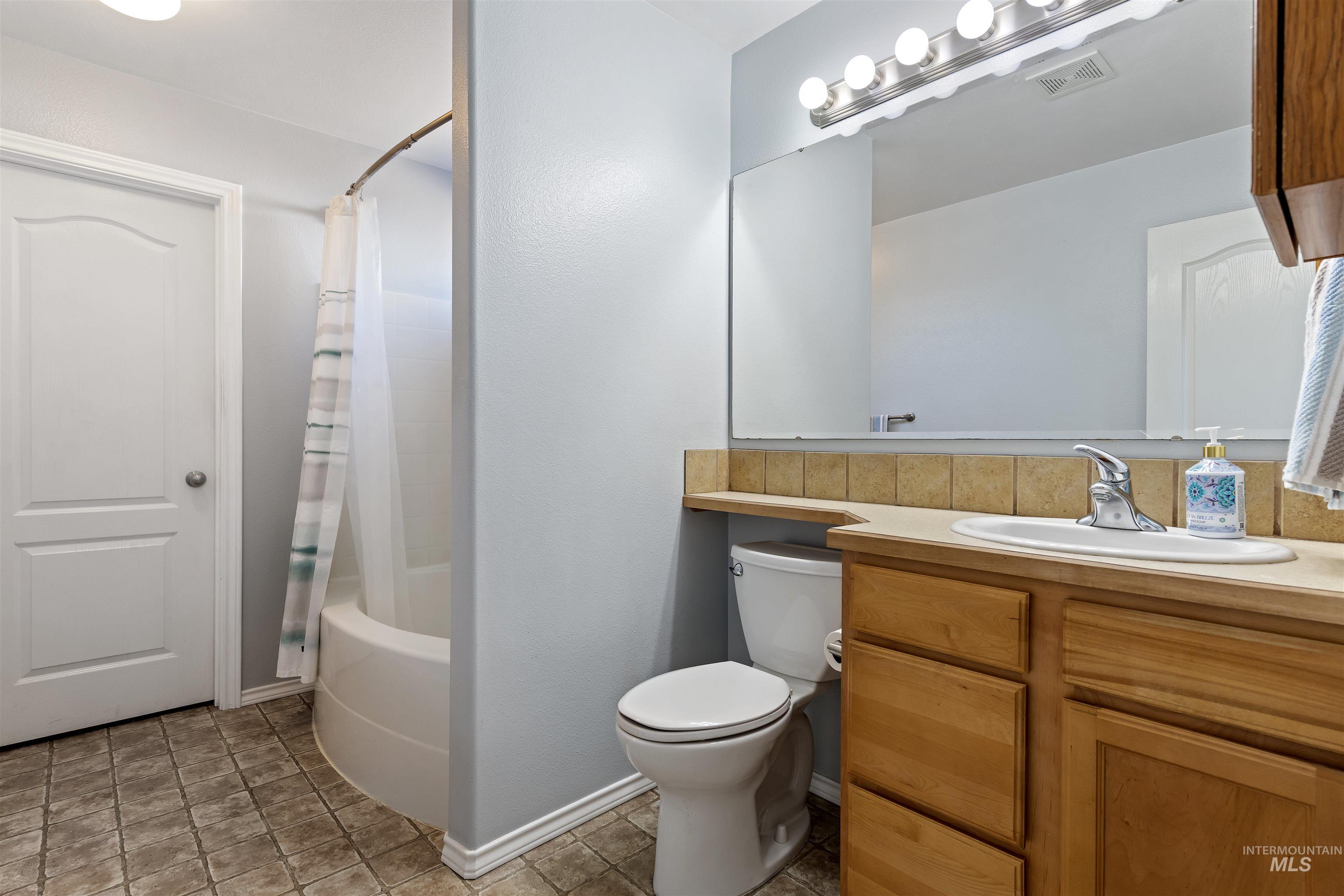 2175 North CapeCod Way Meridian, ID 83646 - Photo 17 of 23 Bathroom featuring a single vanity with wood cabinetry, a large mirror, and a full bathtub with shower