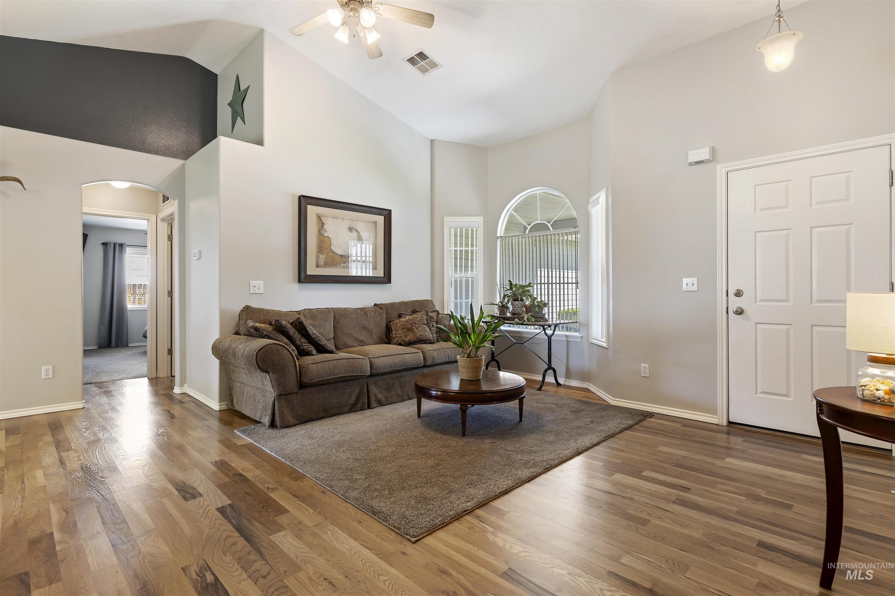 2175 North CapeCod Way Meridian, ID 83646 - Photo 5 of 23 Expansive living area featuring vaulted ceilings, wood-finish flooring, and an arched transom window