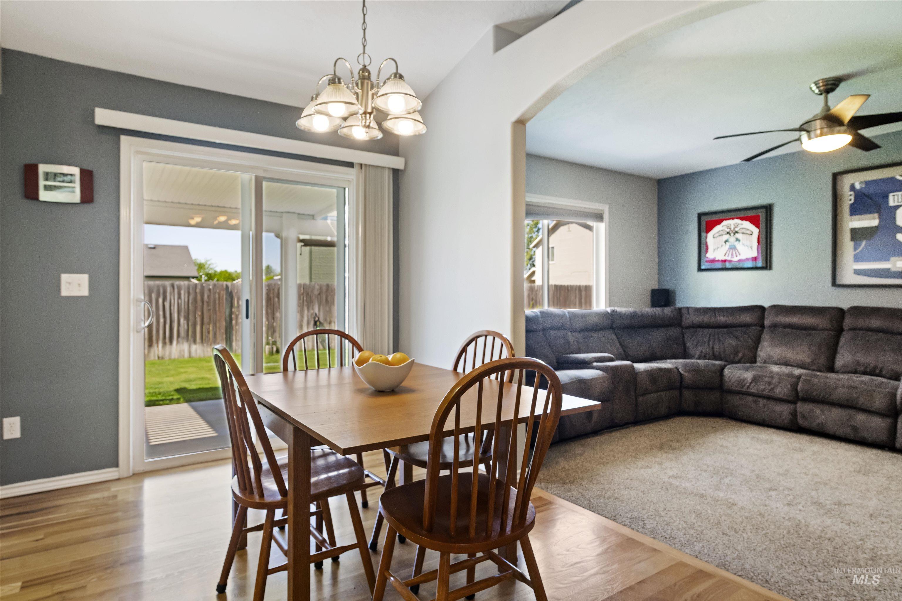 2175 North CapeCod Way Meridian, ID 83646 - Photo 8 of 23 Dining area featuring wood-finish flooring, a contemporary chandelier, and direct access to the backyard through sliding glass doors
