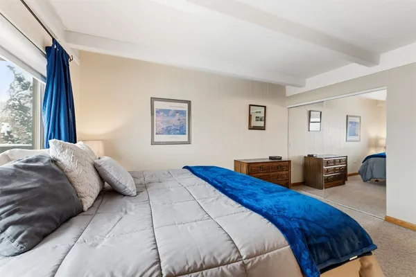 a bedroom with bed and a large mirror next to a window