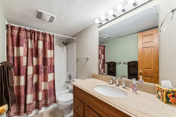 a bathroom with a granite countertop sink toilet and shower