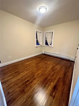 a view of an empty room with wooden floor and cabinet