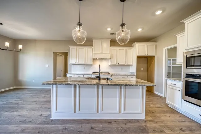 a kitchen with stainless steel appliances granite countertop a sink a stove and a wooden floors