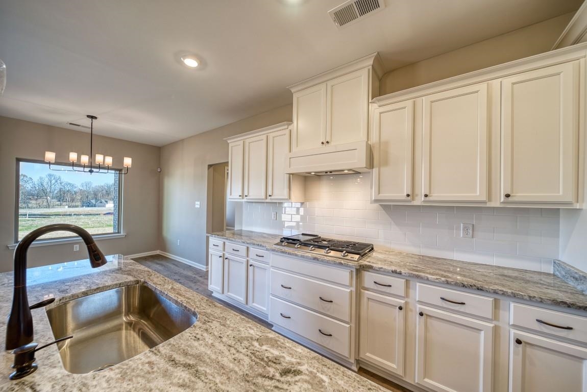 142 Como Lane Atoka, TN 38004 - Photo 8 of 33 a kitchen with granite countertop a stove a sink and white cabinets