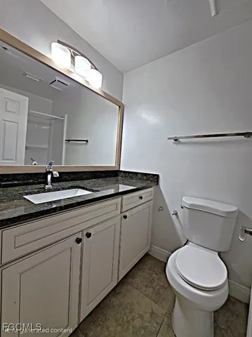 a bathroom with a granite countertop toilet sink and mirror