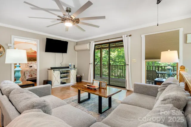 a living room with furniture a ceiling fan a fireplace and a large window