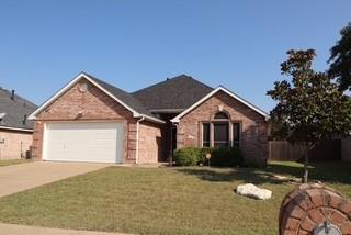 Home featuring a front lawn, driveway, a garage, and brick siding.