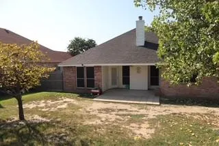 a view of a house with a yard and large tree