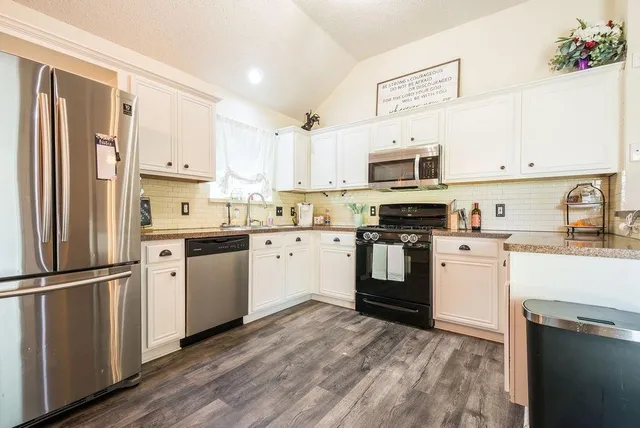 a kitchen with granite countertop a refrigerator stove top oven and sink