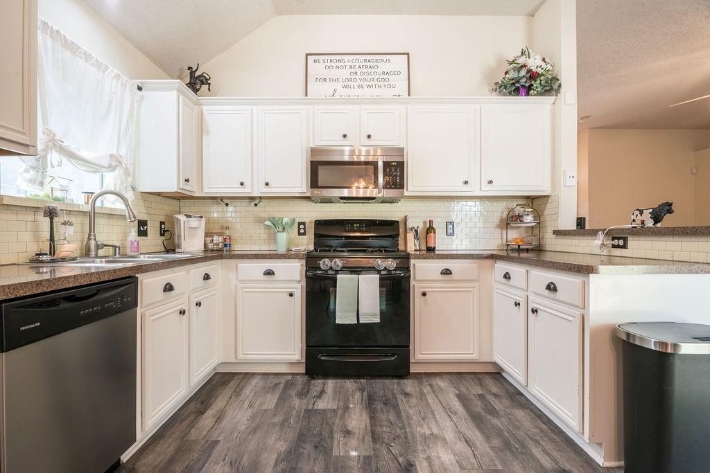 3029 Canary Lane Midlothian, TX 76065 - Photo 9 of 21 Kitchen featuring stainless steel appliances, dark wood-style flooring, backsplash, white cabinets, and lofted ceiling