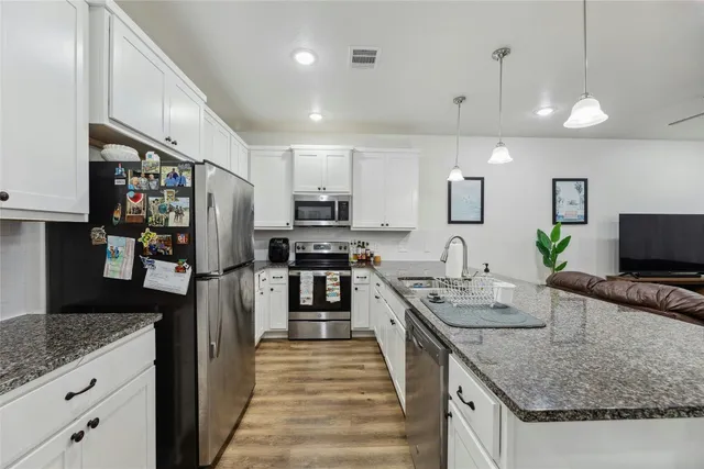 a kitchen with stainless steel appliances granite countertop a sink refrigerator and microwave