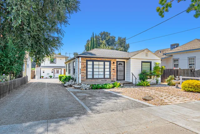 a front view of a house with a yard and potted plants