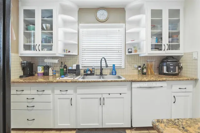 a kitchen with granite countertop white cabinets and window