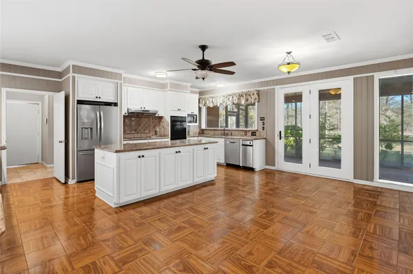 a large kitchen with stainless steel appliances a large counter top and white cabinets