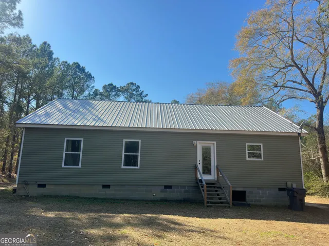 a view of a house with a barbeque and wooden fence