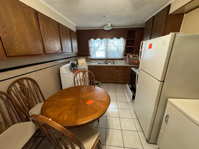 a kitchen with stainless steel appliances a stove a refrigerator and a dining table with wooden floor