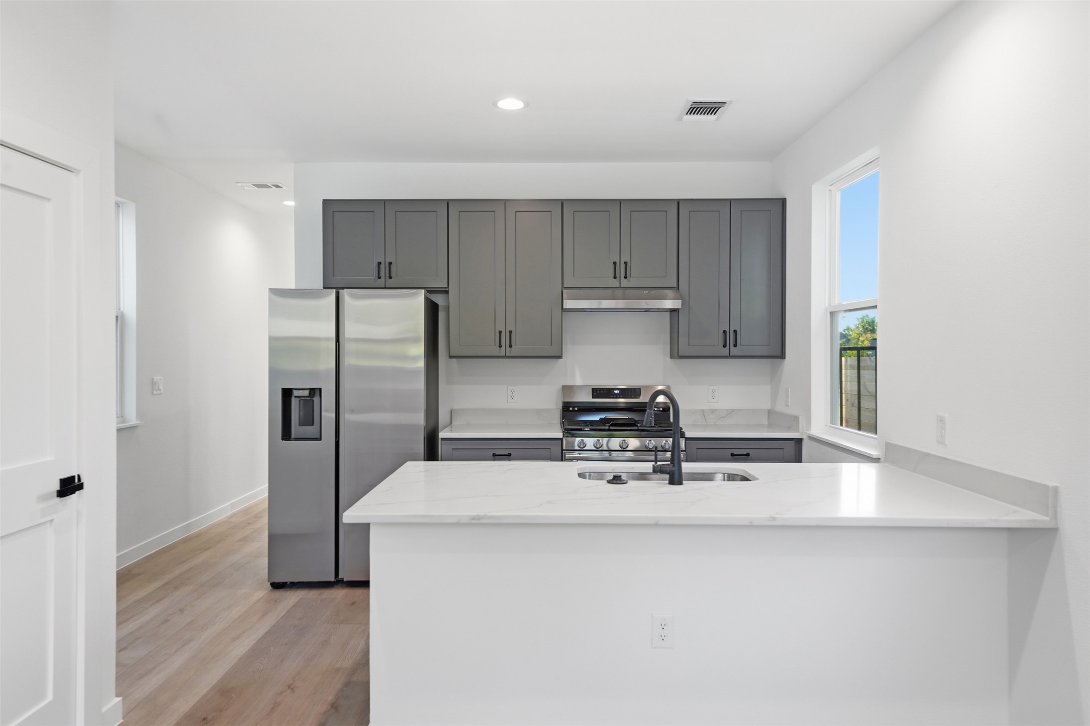 2212 Yellow Jacket Lane, Unit 2 Austin, TX 78741 - Photo 10 of 25 Modern kitchen featuring grey cabinetry, stainless steel appliances, and white stone countertops