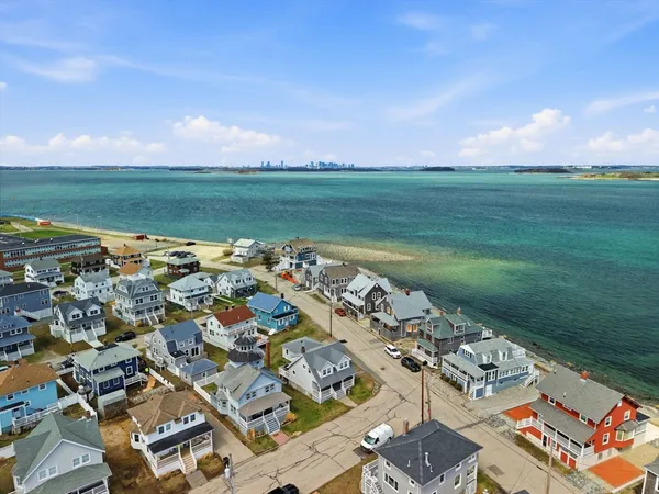an aerial view of a city with lots of residential buildings and ocean view in back