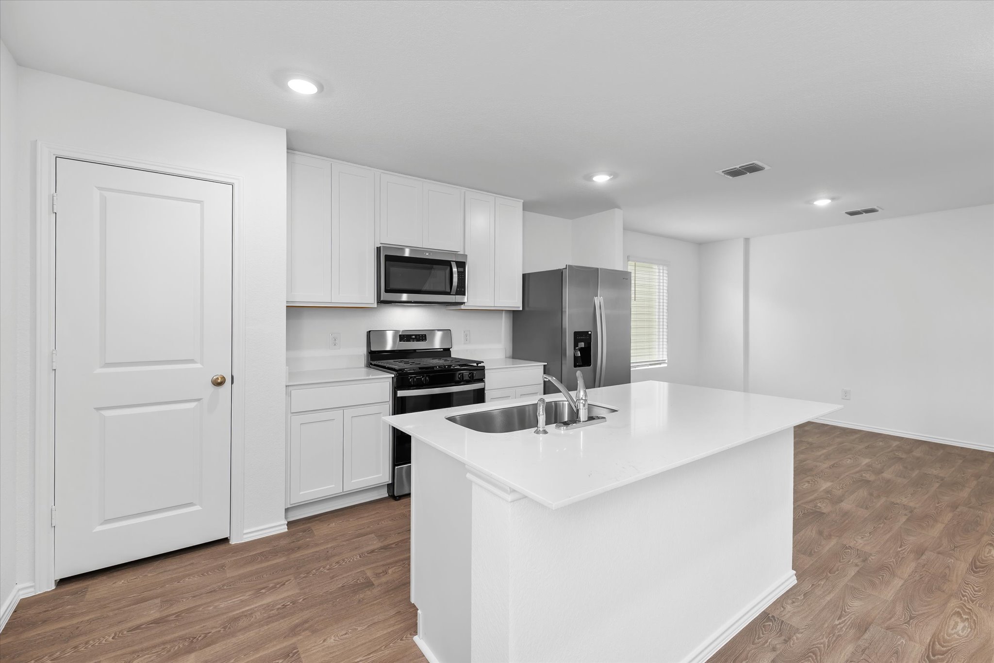 456 Sandringham Loop Kyle, TX 78640 - Photo 31 of 40 A pristine white kitchen features a spacious island and modern stainless steel appliances.