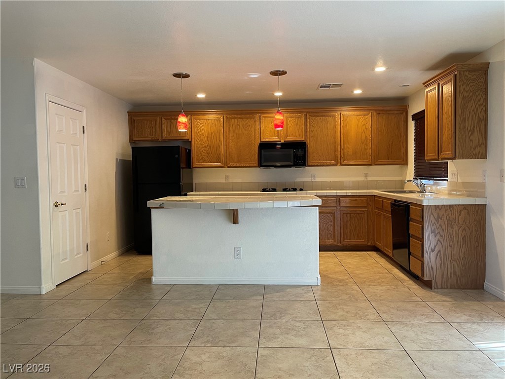 9975 Willowbrook Pond Road Las Vegas, NV 89148 - Photo 8 of 18 Kitchen with tile counters, black appliances, hanging light fixtures, brown cabinetry, and recessed lighting