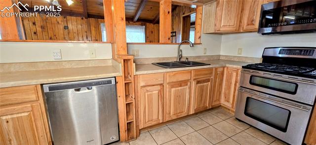 11785 Milam Road Colorado Springs, CO 80908 - Photo 20 of 44 Kitchen with appliances with stainless steel finishes, light countertops, light tile patterned floors, and a wooden ceiling with exposed beams