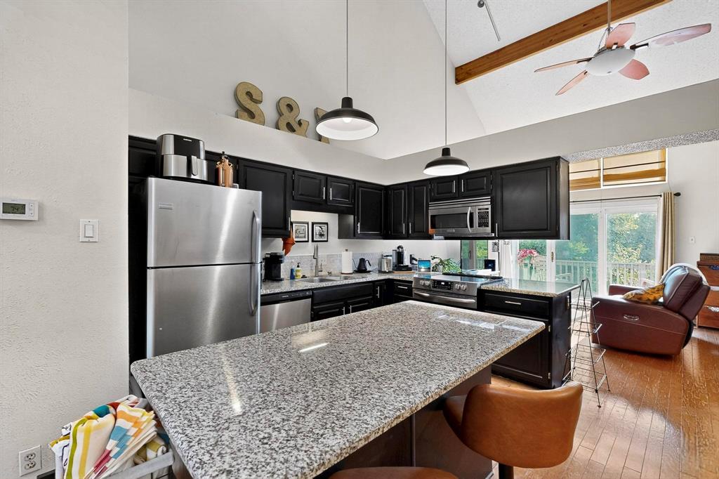 a kitchen with stainless steel appliances granite countertop a sink refrigerator stove and microwave