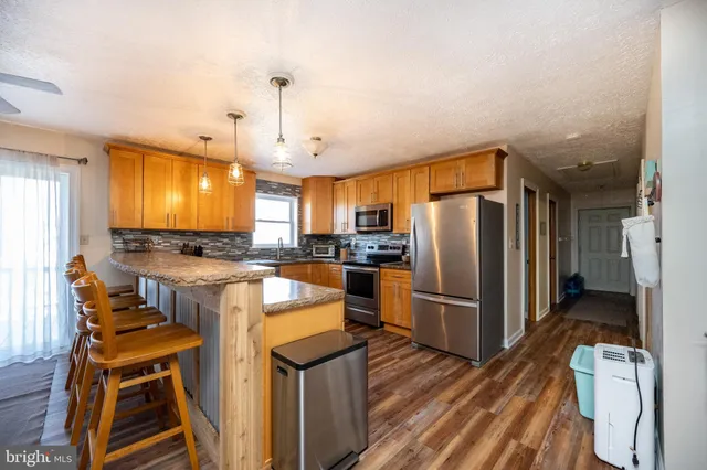 a large kitchen with cabinets chairs and wooden floor
