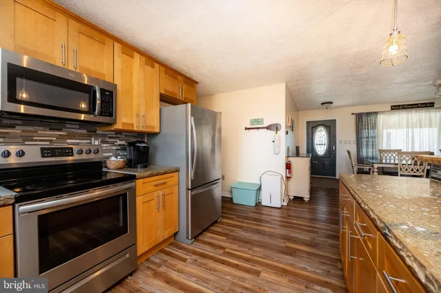 a kitchen with stainless steel appliances kitchen island granite countertop a table chairs sink and cabinets