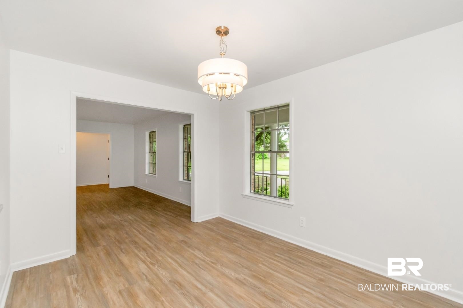 5217 Perin Road Mobile, AL 36693 - Photo 15 of 45 Spacious room featuring wood-finish flooring, white walls, and a contemporary drum chandelier
