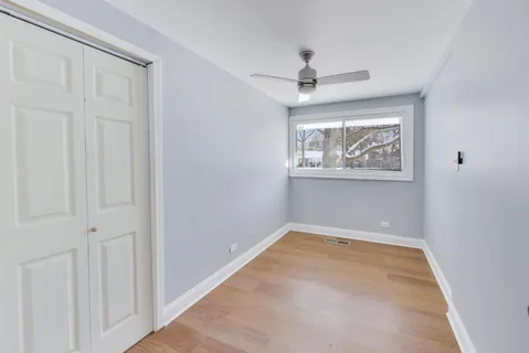 an empty room with windows and fan