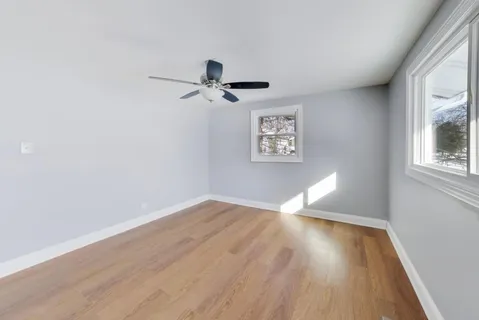 a view of empty room with wooden floor and fan