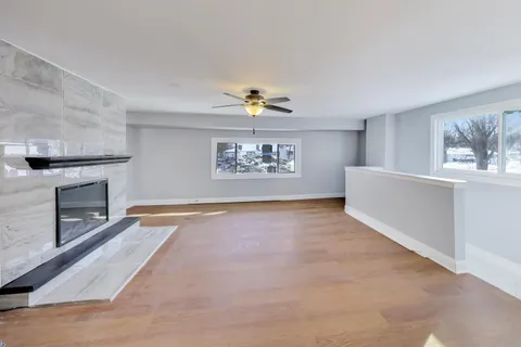 an empty room with windows and fireplace