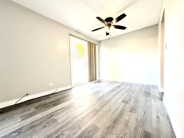 an empty room with wooden floor and a ceiling fan