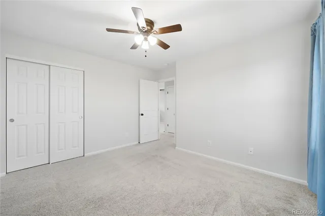 an empty room with a chandelier fan and closet area