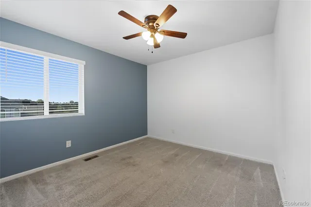 an empty room with windows and ceiling fan