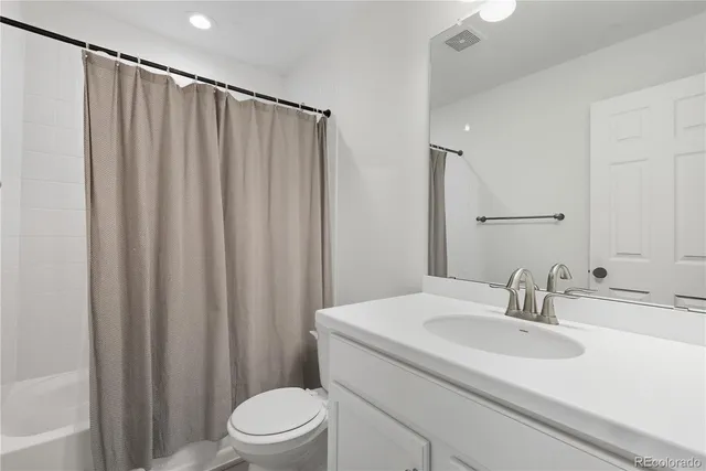 a bathroom with a sink a toilet a mirror and shower curtain