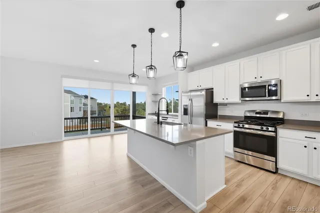 a kitchen with stainless steel appliances granite countertop a sink a stove and a wooden floors