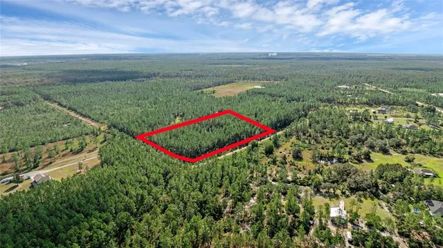 a view of a field with an ocean and trees in the background