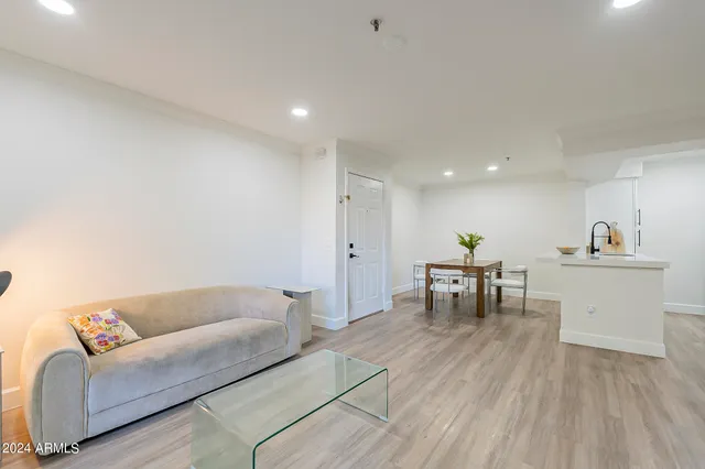 a living room with furniture and a dining table with wooden floor