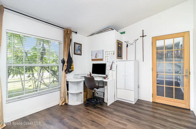 a view of a workspace with wooden floor and a window