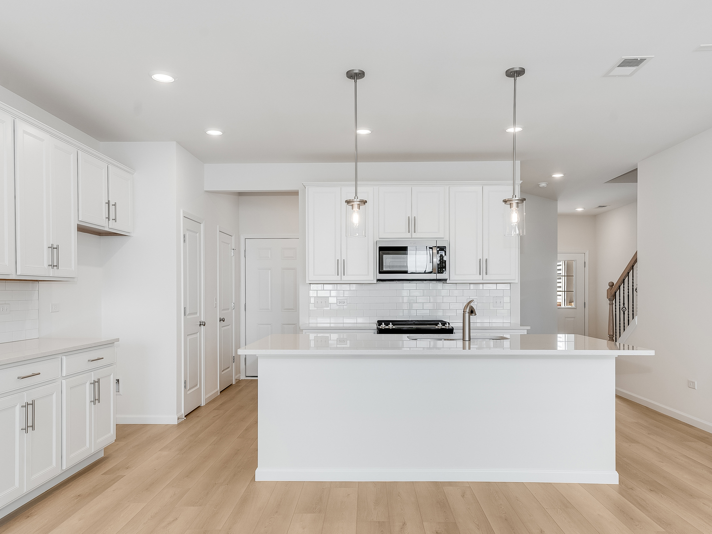 660 Switchgrass Way, Unit 58002 Bolingbrook, IL 60490 - Photo 4 of 24 a kitchen with stainless steel appliances kitchen island granite countertop a sink a stove a refrigerator and white cabinets with wooden floor