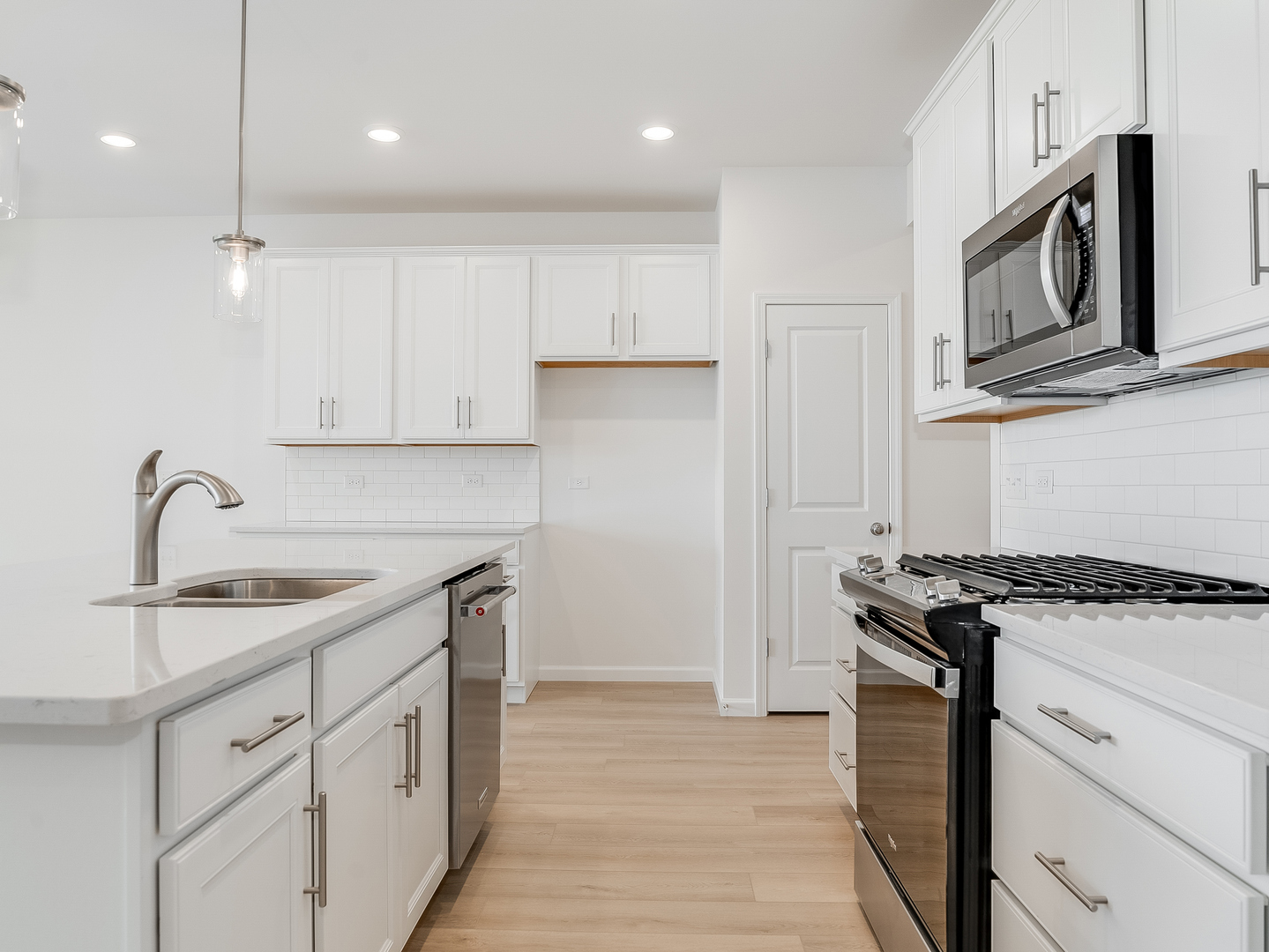660 Switchgrass Way, Unit 58002 Bolingbrook, IL 60490 - Photo 8 of 24 a kitchen with stainless steel appliances granite countertop a sink stove oven and white cabinets with wooden floor